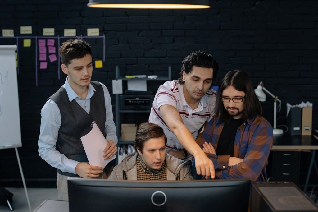 services-01 Group of professionals discussing a project at a computer in a modern office environment.